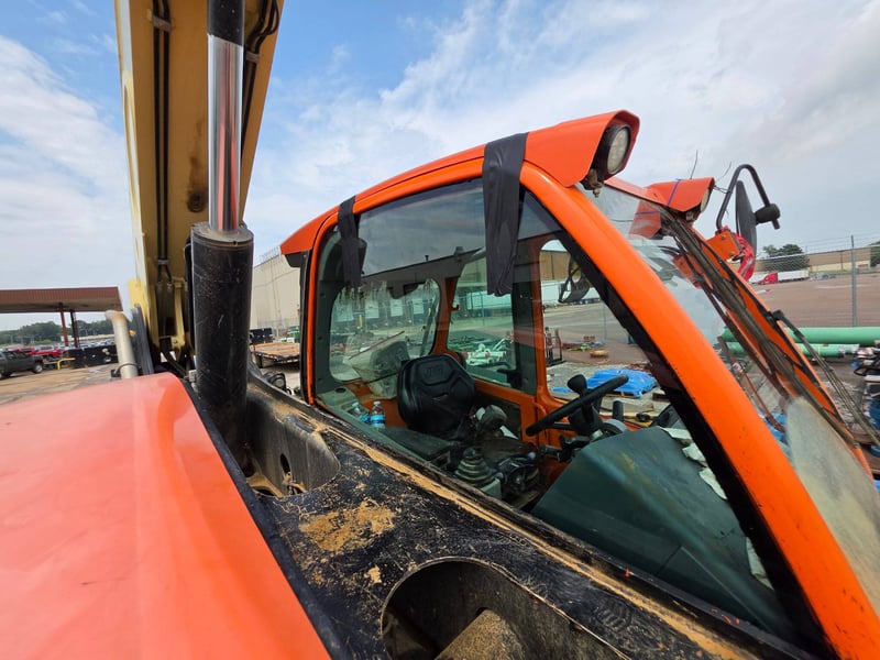 The same telehandler with new cab glass installed and taped at the edges while the urethane cures