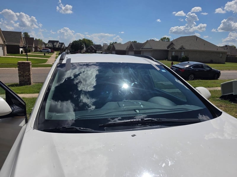 The same white SUV with a newly installed windshield, photographed in the driveway where the work was done