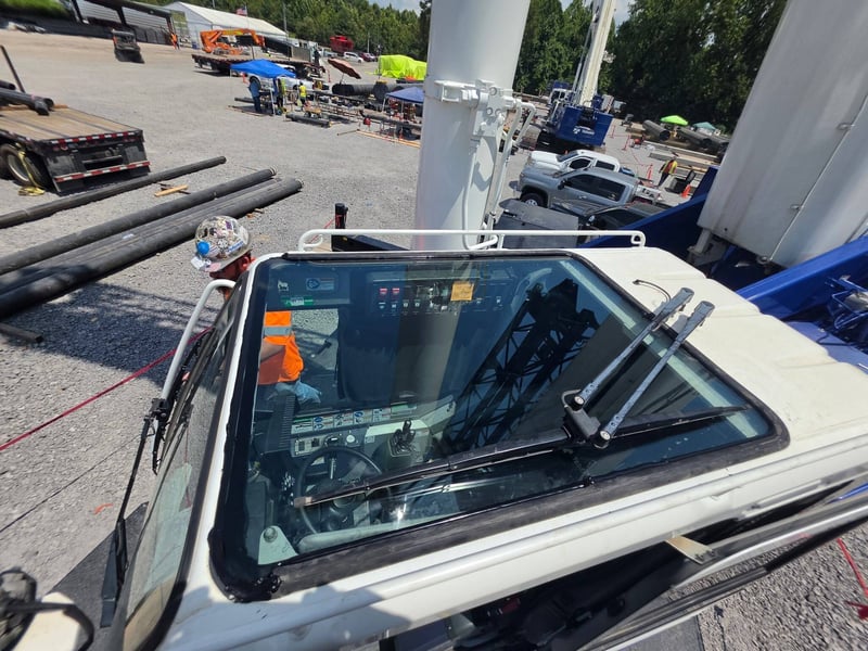 The same boom crane back at work on a pipe yard job site after the cab glass was replaced