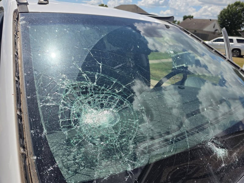 Shattered windshield on a white SUV with a large impact break on the driver's side, before replacement